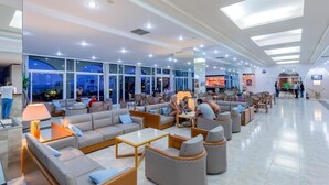 A spacious lobby with modern seating areas, large windows, and a well-lit ceiling. - Olympos Beach (Rhodes)