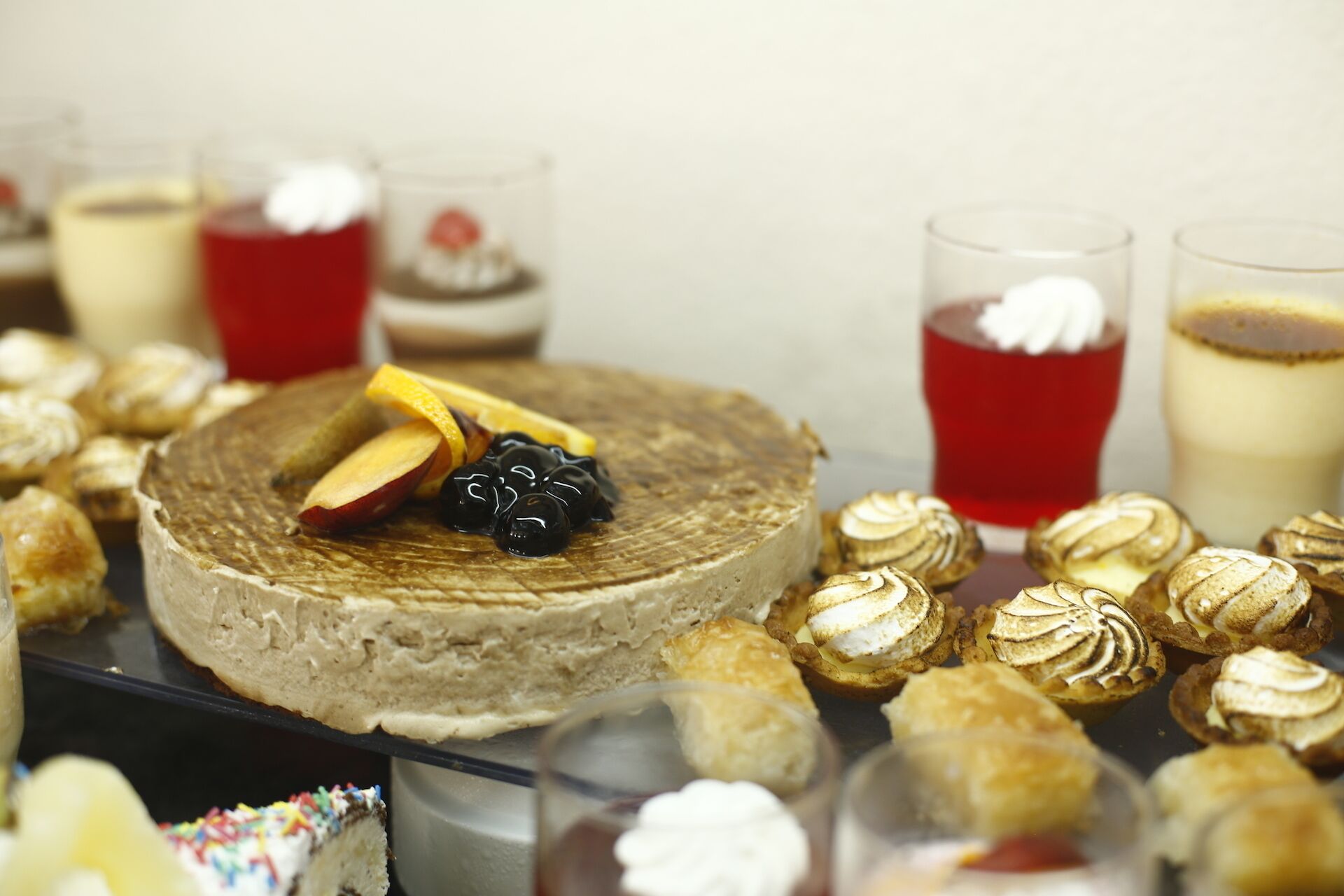 Variedad de postres, incluyendo un pastel grande, pastelería y bebidas, sobre una mesa.