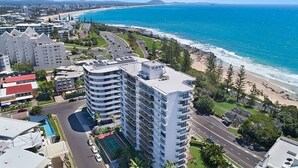 Un hotel moderno de gran altura con varias plantas, una piscina en la azotea y vistas a la playa y al océano.