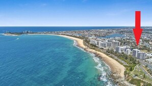 Vista aérea de una ciudad costera con una playa, edificios altos y un faro.