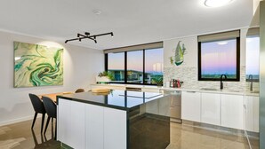 Una cocina moderna con una isla central, ventanas amplias y vistas a un puente.