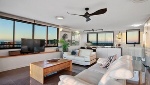 Una sala de estar moderna con televisor, sofá, mesa de centro y ventilador de techo.