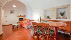 Un espace repas comprenant une table en bois, des chaises et une arche en pierre.