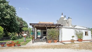 Une petite maison avec un toit en tuiles, une véranda et des plantes en pot.