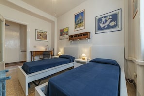 A hotel room with two beds, a desk, a chair, and a small cabinet.