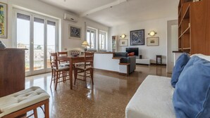 A spacious living area with a dining table, chairs, a sofa, and a bookshelf. - Roomy and Bright Apartment With Terrace (Roma)