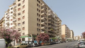 A multi-story building with balconies, a pharmacy, and parked cars. - Roomy and Bright Apartment With Terrace (Roma)