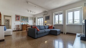 A spacious living area with a grey sectional sofa, a white sofa, a dining table with chairs, and artwork on the walls. - Roomy and Bright Apartment With Terrace (Roma)