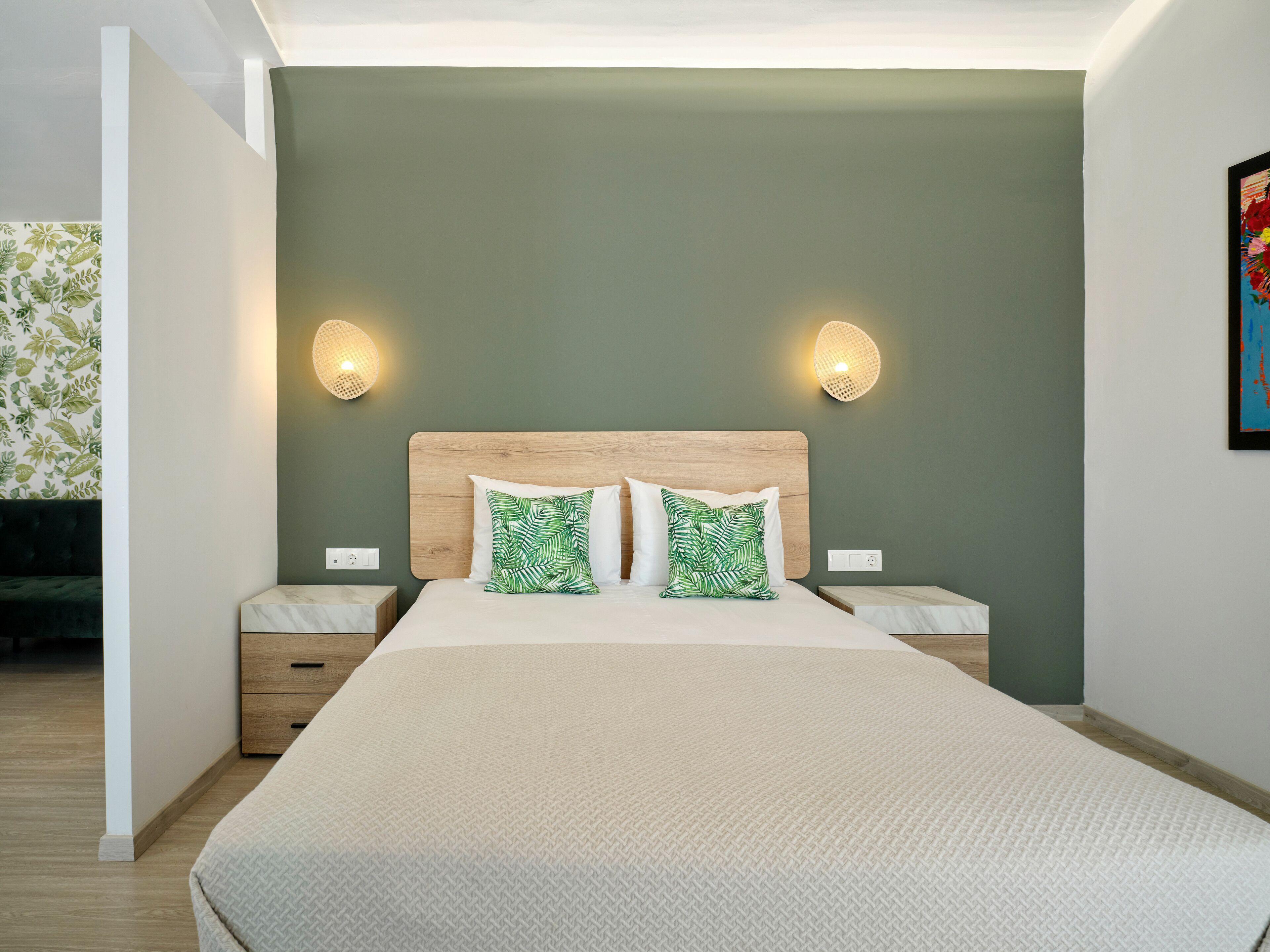 A modern bedroom with a large bed, two bedside tables, and a green wall.