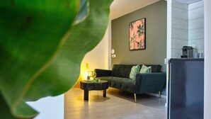 Una sala de estar moderna con un sofá verde oscuro, una mesa de centro de madera y un cuadro en la pared.