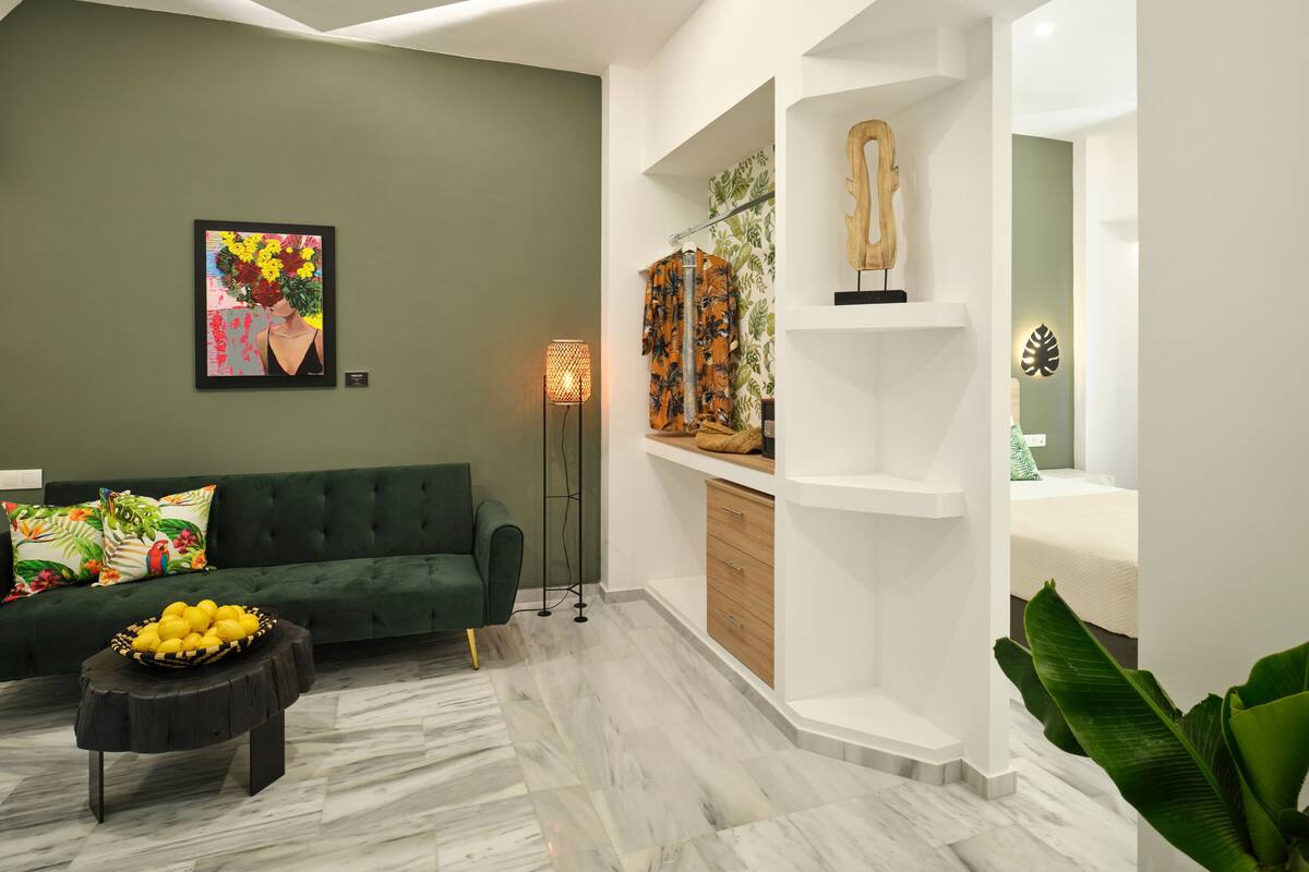 A modern living room with a green sofa, a floor lamp, and a wall-mounted shelf with decorative items.