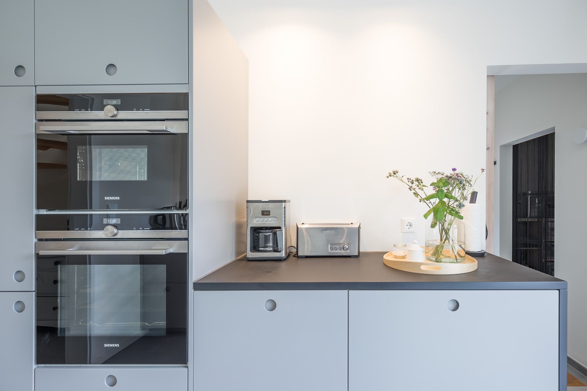 A modern kitchen with a built-in oven, a coffee machine, and a toaster.