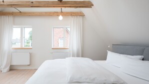 A bedroom with a bed, a window, a radiator, and a view of a brick building. - Vacation home Fischerhaus in Tönning for up to 6 people (Tönning)