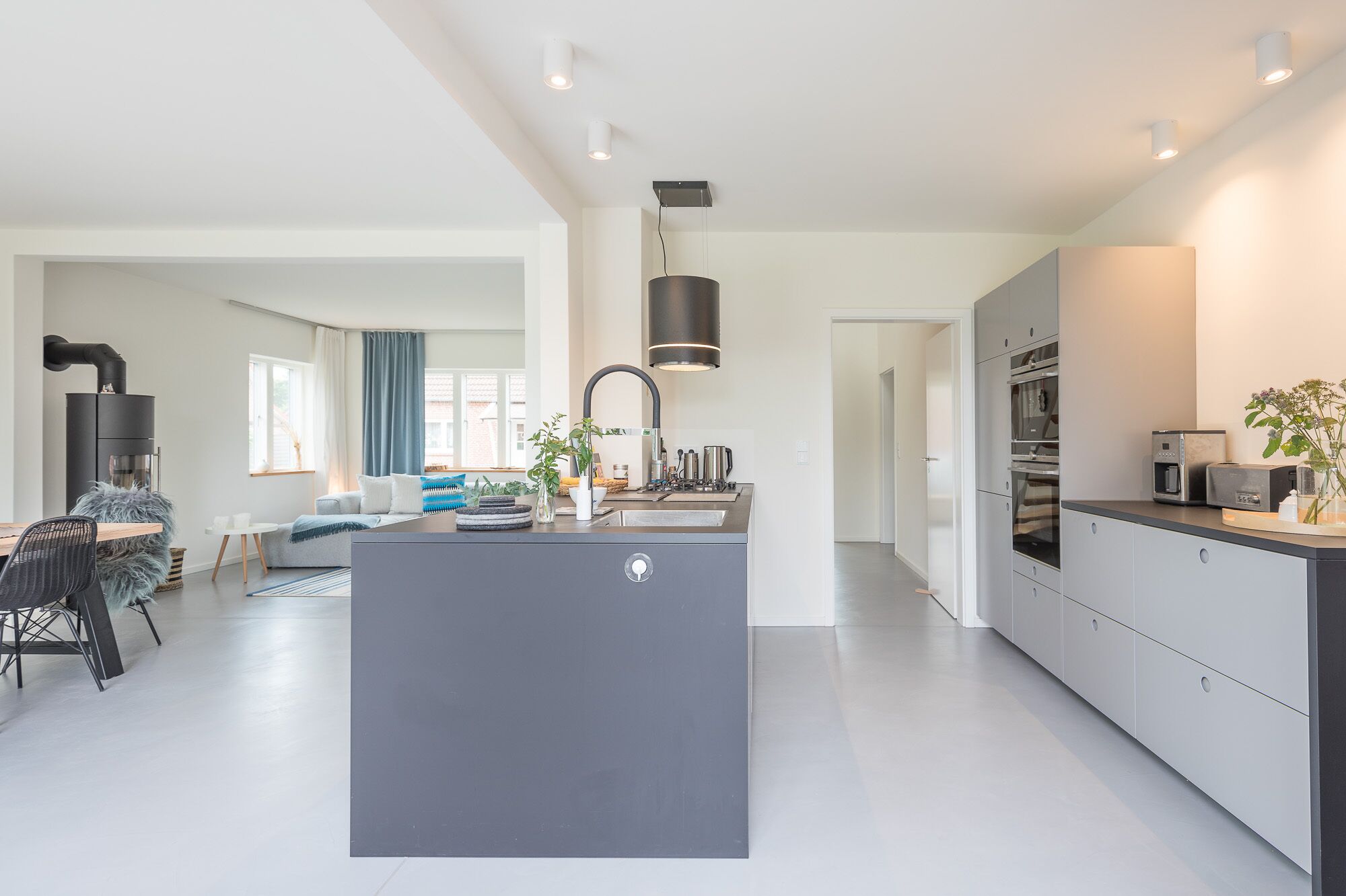 Une cuisine moderne dotée d’un îlot central, d’appareils électroménagers intégrés et d’un coin repas comprenant un canapé et des chaises.