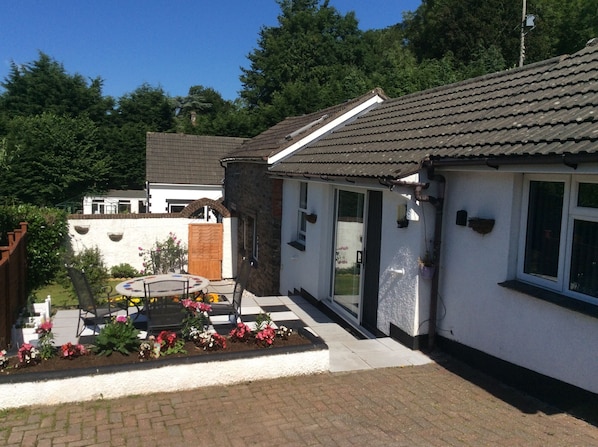 Enjoy a peaceful retreat in this serene garden setting, surrounded by lush greenery and a beautifully manicured flower bed.