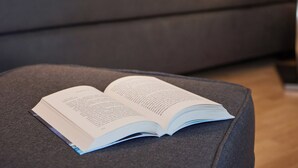 Una sala de estar moderna con un sofá gris, un reposapiés negro y un libro encima.