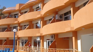 Hotel com vários andares, varandas, aparelhos de ar condicionado e guarda-corpo azul.