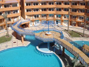 A multi-story hotel with a central pool area featuring a spiral water slide and surrounding walkways. - Apartment B17, 88 square meters, with 2 bedrooms (Hurghada)