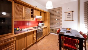 A modern kitchen with wooden cabinets, a gas stove, and a dining table with chairs. - Apartment in HEART of Wroclaw-Townhall (Wroclaw)