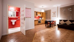 A modern kitchen with wooden cabinets, a dining area with a table and chairs, and a living room with a sofa. - Apartment in HEART of Wroclaw-Townhall (Wroclaw)