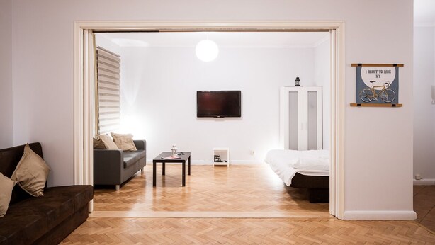 A modern living room with a sofa, a coffee table, and a bed. There is a television mounted on the wall and a framed picture on the wall. - Apartment in HEART of Wroclaw-Townhall (Wroclaw)