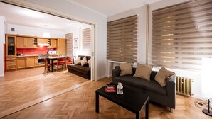 A modern living room with a sofa, a coffee table, and a kitchen in the background. - Apartment in HEART of Wroclaw-Townhall (Wroclaw)