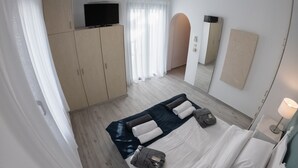 Una habitación de hotel moderna con cama, televisión, armario y espejo.