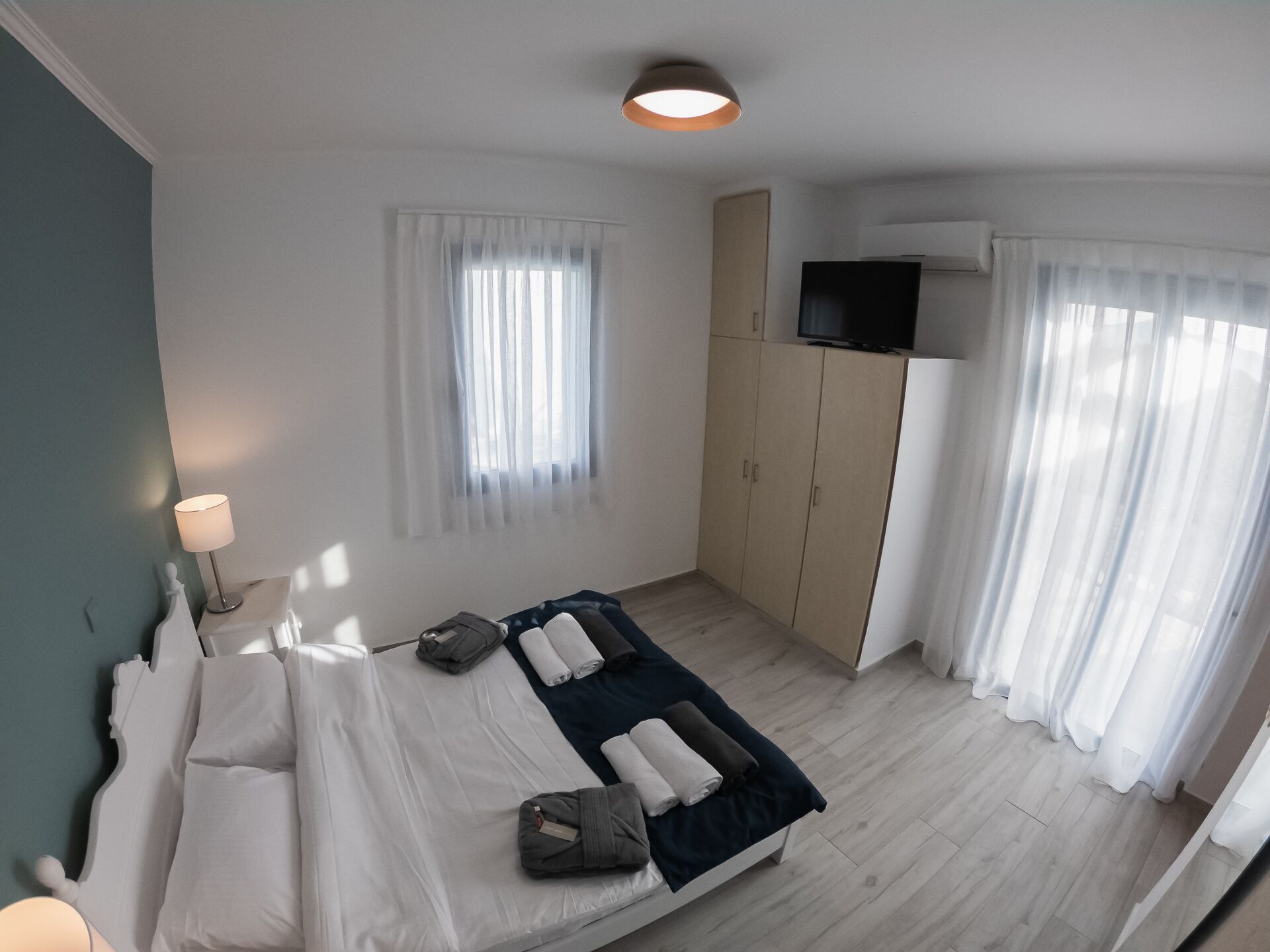 Un dormitorio moderno con cama, televisión y armario.