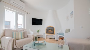Een moderne woonkamer met een glazen salontafel, een bank, een televisie en een open haard.