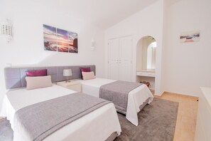 Een moderne slaapkamer met twee bedden, een kledingkast, een spiegel en kunst aan de muren.