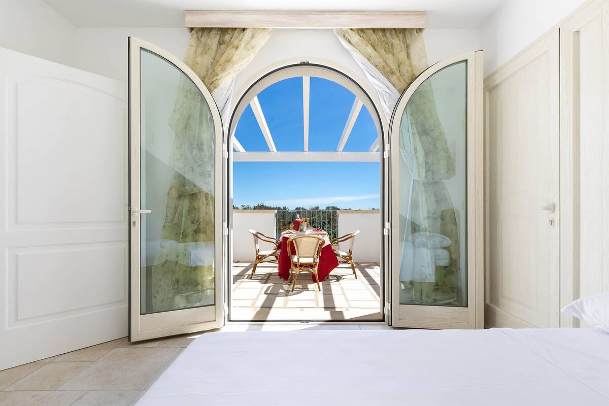 A room with a large glass door leading to an outdoor patio with a table and chairs.