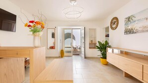 Ein modernes Wohnzimmer mit einer Holzbank, einem Glastisch, einer Vase mit Blumen, einem großen Gemälde und einer Uhr an der Wand.