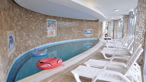 An indoor swimming pool with clear water, white lounge chairs, and dolphin-themed wall art. - Self contained forest view luxury apartments  (Kusadasi)