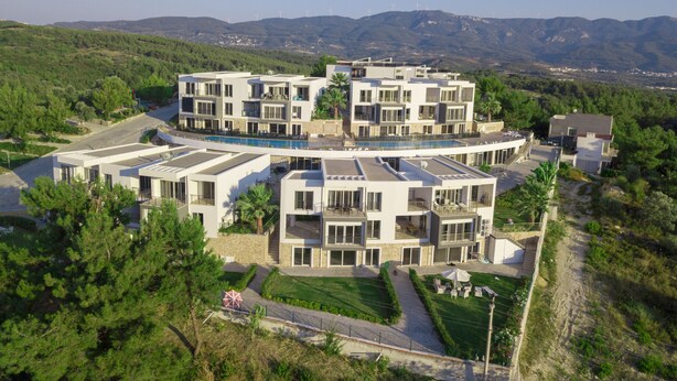 A modern multi-story hotel with a pool, surrounded by greenery and mountains. - Self contained forest view luxury apartments  (Kusadasi)