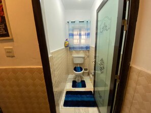 A small bathroom with a toilet, a sink, and a shower area.
