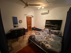 A bedroom with a bed, a dresser, a ceiling fan, an air conditioner, and a clock on the wall.