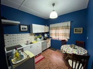 A compact kitchen with blue walls, white cabinets, and a dining area with a table and chairs.