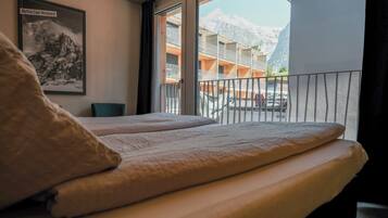 Ein Hotelzimmer mit Bett, Fenster mit Bergblick und einem gerahmten Bild an der Wand.