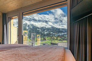 Una habitación con un amplio ventanal que ofrece vistas a montañas nevadas y un pueblo en la falda.