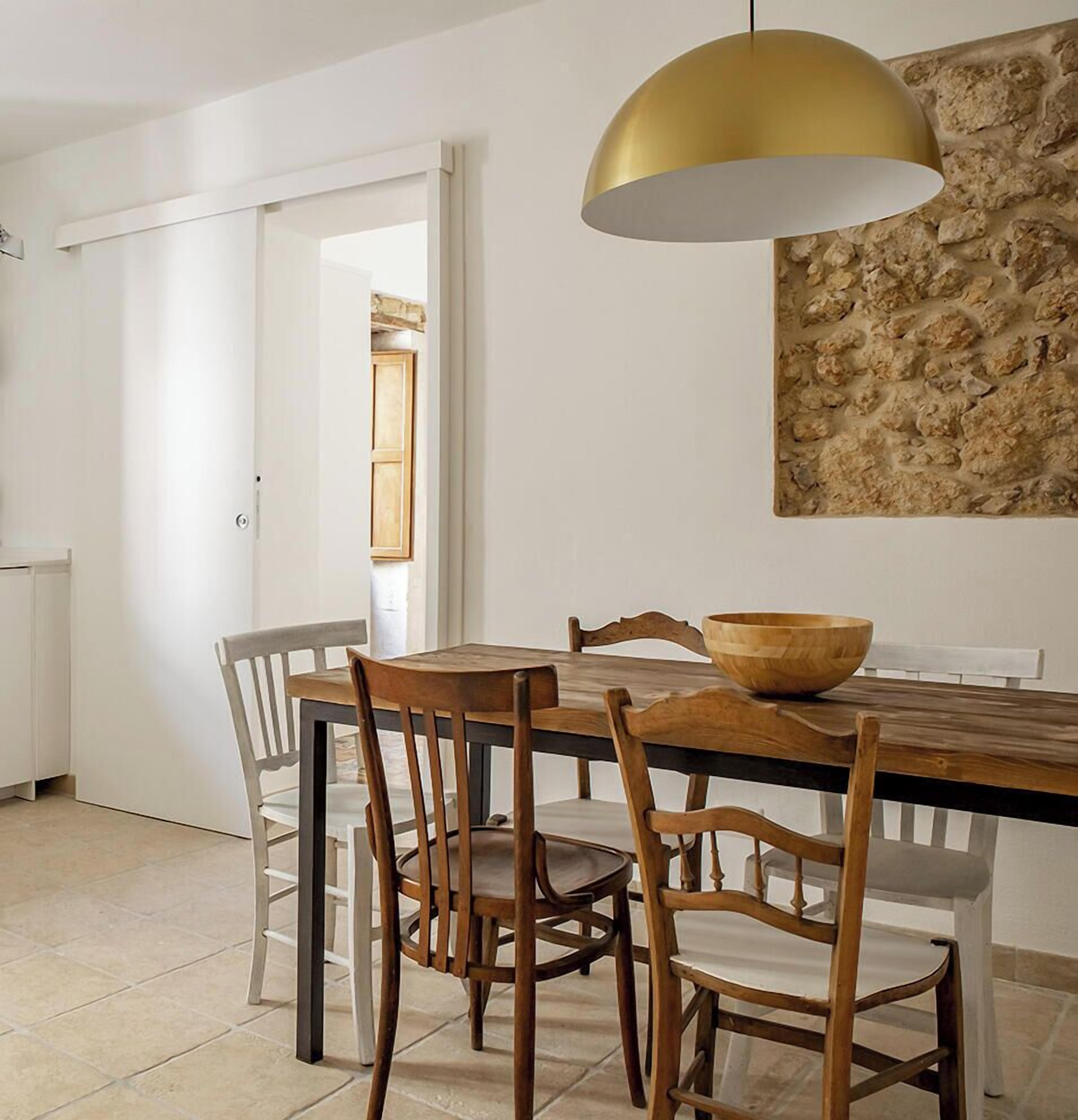 Una cocina moderna con armarios blancos, horno integrado y comedor con mesa y sillas de madera.
