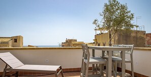A rooftop terrace with a table and chairs, a lounge chair, and a view of the cityscape. - La Terrazza sul Vicolo della Giudecca by Wonderful Italy (Siracusa)