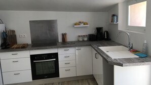 Een moderne keuken met witte kastjes, een ingebouwde oven, een spoelbak en een koffiezetapparaat.