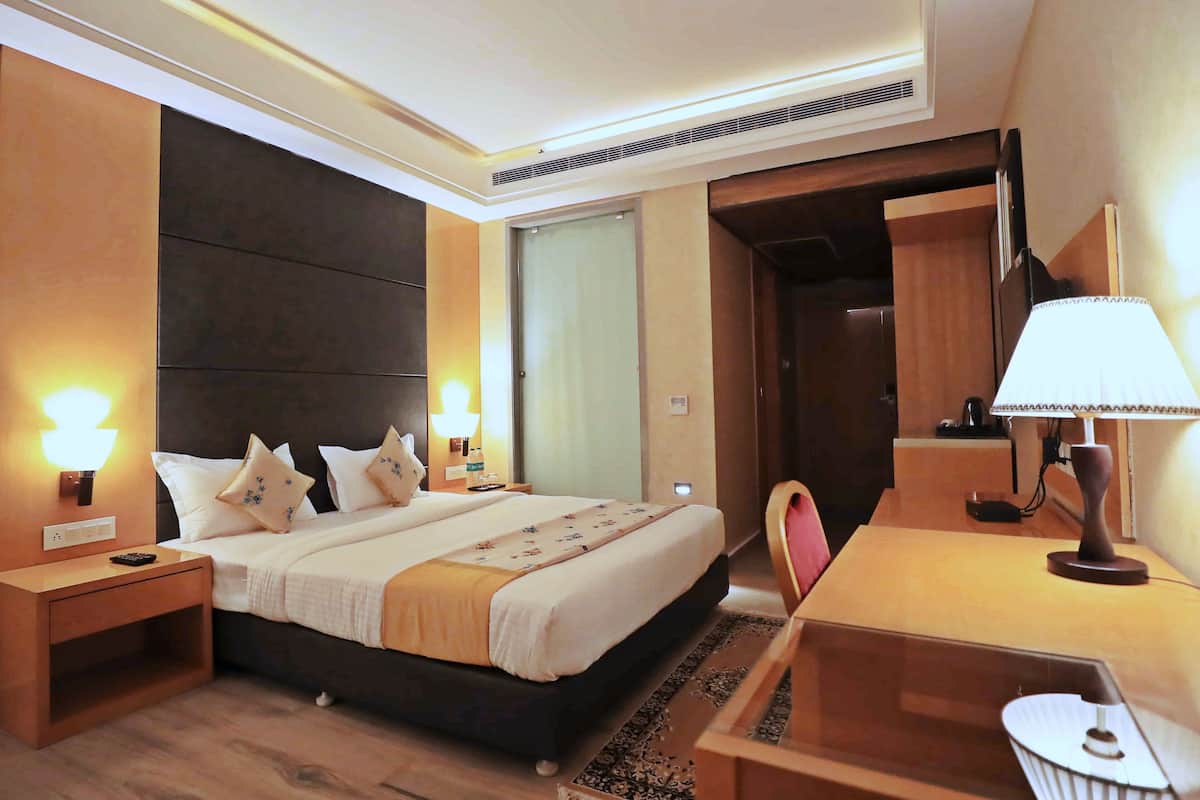 Quarto de hotel com uma cama grande, mesas de cabeceira, uma escrivaninha e uma cadeira.