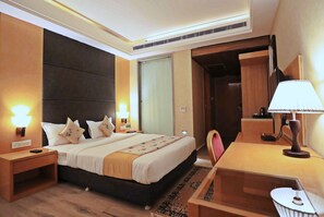 Une chambre d’hôtel avec un grand lit, des tables de chevet, un bureau et une chaise.