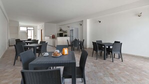 A spacious dining area with multiple tables and chairs, a kitchen area with modern appliances, and a view of the outdoors. - 1786 B&B Joy Home - Camera 2 (Maruggio)