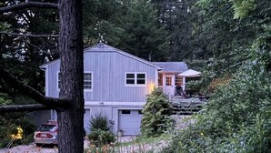 A two-story house with a garage, surrounded by dense forest. - Peacock Garden Cottage - Discounted for Winter Month Rental (Pine plains)