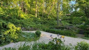A garden with a gravel path, dense greenery, and trees. - Peacock Garden Cottage - Discounted for Winter Month Rental (Pine plains)