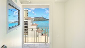Un balcon avec vue sur une plage et une montagne.