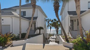 A beachfront property with two-story buildings, a staircase leading to the entrance, and palm trees. - Remodeled Seagrove Condo ~ Pool ~ Steps to Beach + Free Attraction Tickets! (Santa Rosa Beach)