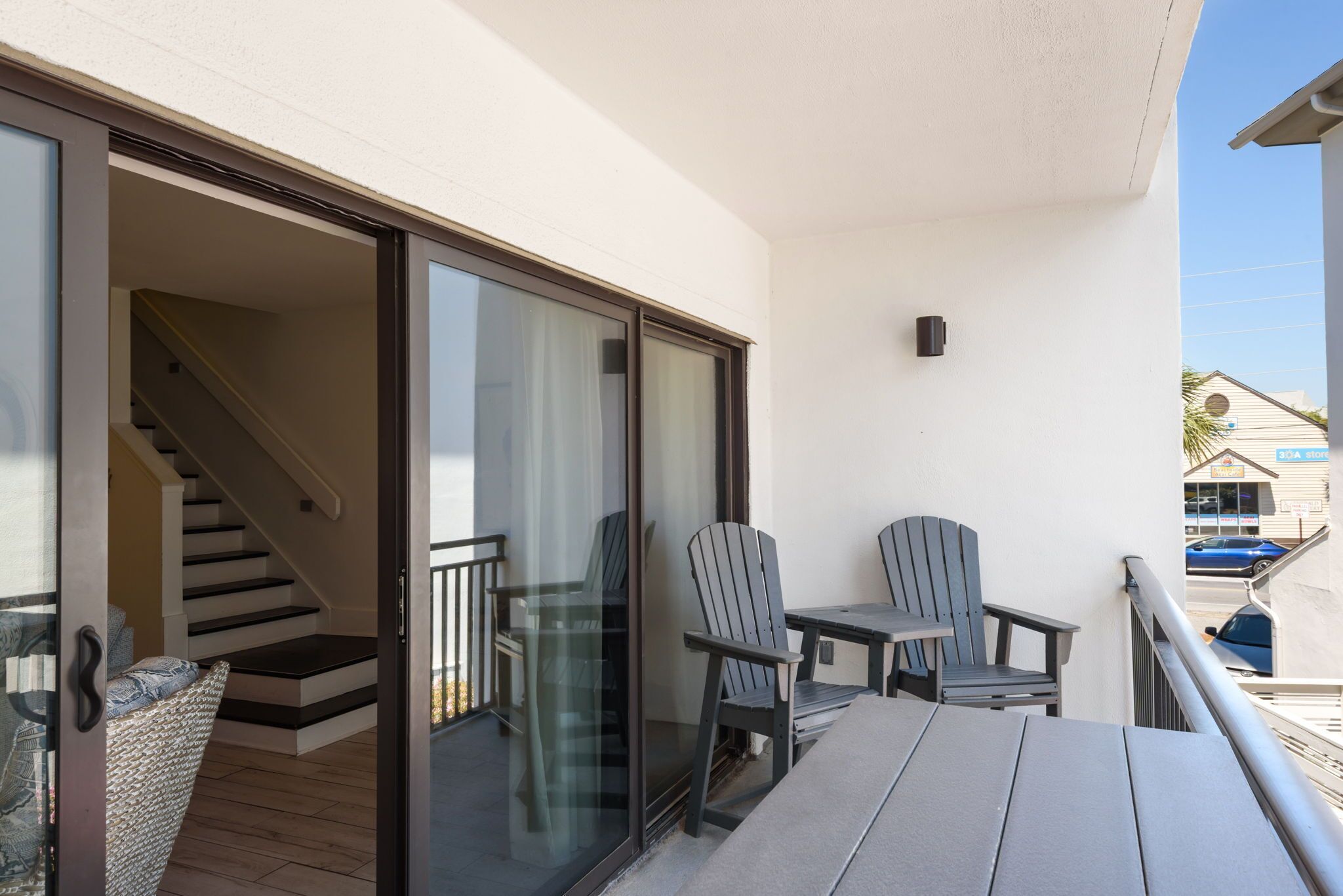 Un balcon avec une table, des chaises et un fauteuil en osier.